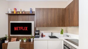 A modern kitchen with a built-in TV displaying 'NETFLIX', a coffee machine, a sink, and a stove. - City Center Porta Venezia New Luxury apt - full equiped - top (Milano)