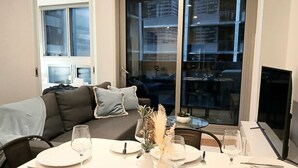 Ein Essbereich mit Tisch für vier Personen, einer Couch und einem großen Fenster mit Blick auf die Stadt.