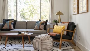 A living room with a sofa, armchair, ottoman, coffee table, and a lamp.