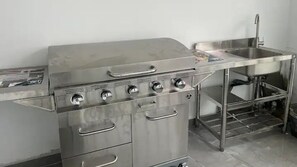 A stainless steel kitchen with four burners, a sink, and a built-in oven.