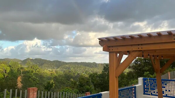 Une pergola en bois offrant une vue sur une colline boisée.