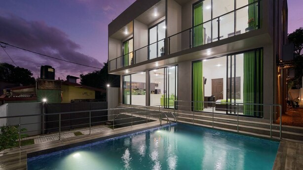Un bâtiment moderne doté d’une piscine, de grandes fenêtres et d’un balcon.