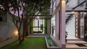 Une maison moderne dotée d’une chambre à coucher entièrement vitrée, d’un petit élément décoratif aquatique et d’un escalier.