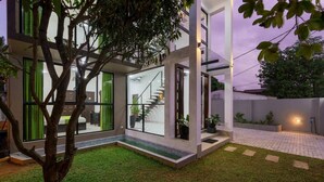 Une maison moderne avec une façade en verre, un escalier apparent et une pelouse bien entretenue.