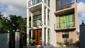 Un immeuble moderne à plusieurs étages, doté d’un toit plat, de grandes fenêtres et d’une entrée sécurisée par un portail.