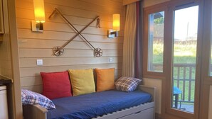 Una stanza piccola con un letto, pareti rivestite in legno e due luci fissate al muro.
