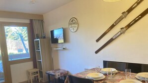 Zona pranzo con tavolo apparecchiato per quattro, televisione a parete e porta sci.