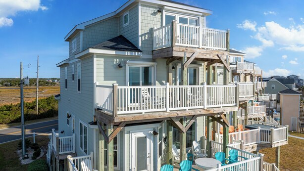 A multi-story house with a hot tub on the ground floor, outdoor seating, and a deck. - At Last - Oceanfront - 5 Bed, 4 Bath -  Pool, Hot Tub, Elevator & Backyard (North Topsail Beach)
