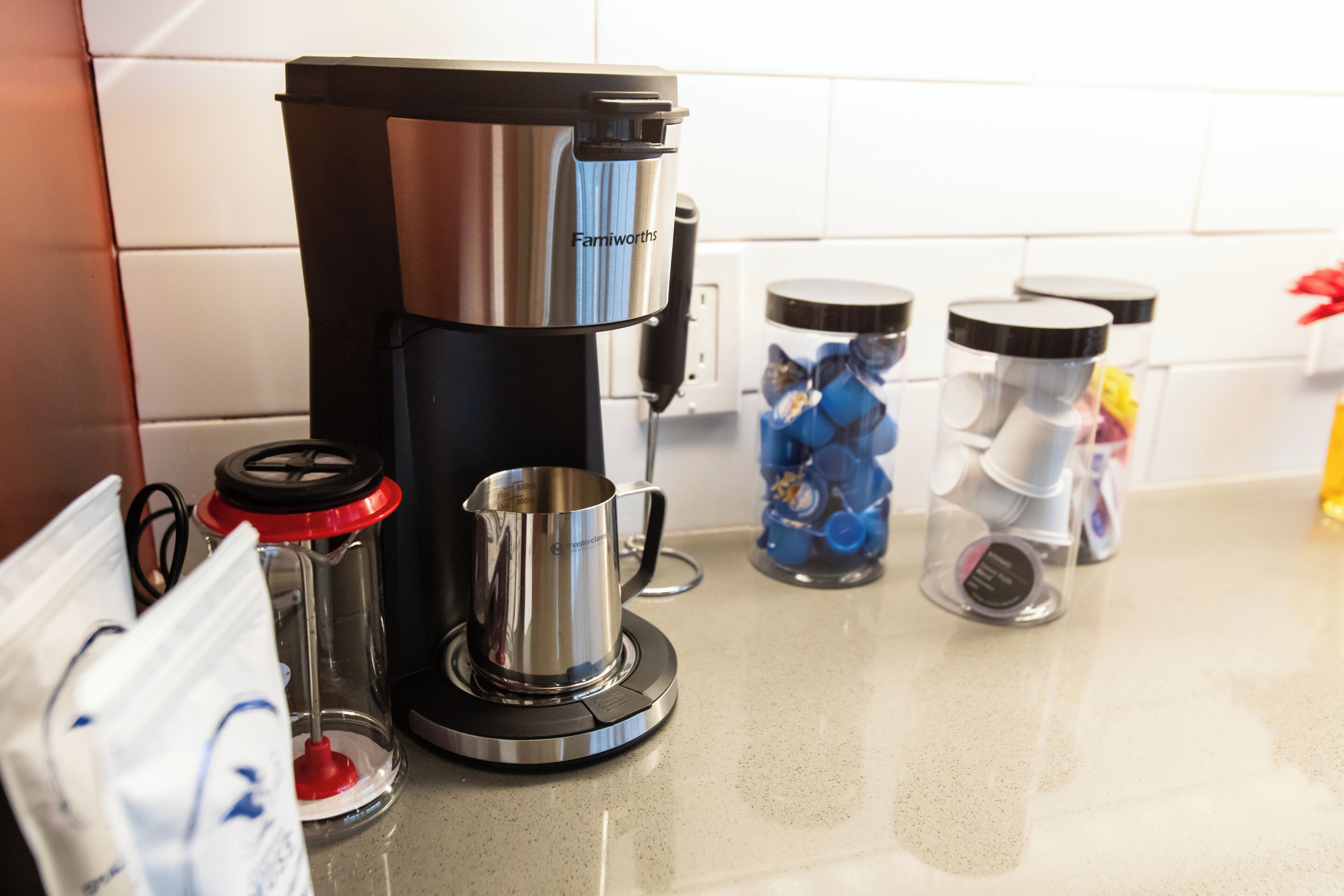 Una cocina con cafetera, dispensador de agua y recipientes con tapas.