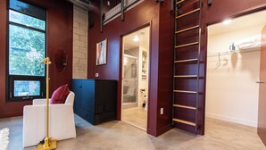 A modern interior with a white sofa, a gold floor lamp, and a red door leading to a bathroom. - Studio loft with garage door with AC located in the heart of DTSA (Santa Ana)