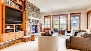 A living room with a stone wall, a flat-screen TV, wooden shelves, a sofa, and a coffee table.