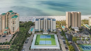 Ein Küstenhotel mit mehreren Hochhäusern, einem Strand und einem Tennisplatz.