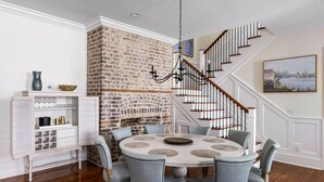Un espace repas avec un mur en briques, un lustre et un escalier.