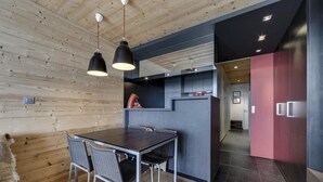 Una cocina moderna con armarios oscuros, techo de madera e iluminación colgante.