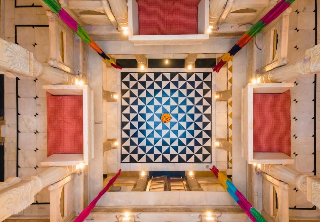 A room with a geometric patterned wall, a central chandelier, and a red curtain.