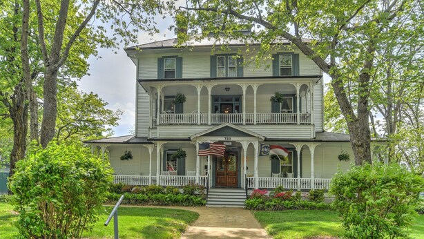 A two-story house with a porch, a front door, and a mailbox.