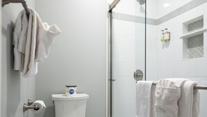A bathroom with a toilet, a glass shower enclosure, and a tiled floor. - Find genuine southern hospitality in Hendersonville at the 1898 Waverly Inn. (Hendersonville)