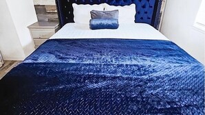 A bed with a blue patterned bedspread, a white pillow, and a headboard with a stone-like design. - Charming 2-bedroom house in fantastic Las Vegas with AC, WiFi Casita los Hermano (Las Vegas)