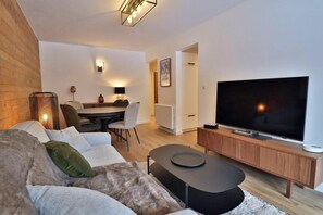 Un salon moderne doté d’un téléviseur à écran plat, d’un canapé, d’une table basse et d’un coin repas avec une table et des chaises.