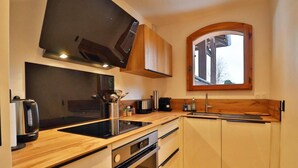 A modern kitchen with wooden cabinets, a black countertop, a built-in oven, and a window with a wooden frame. - Wifi, Ground floor, balcony, tv, 43m², Les Gets (Les Gets)
