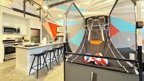 Eine moderne Küche mit Barbereich, einem Basketballkorb und einem Trampolin.