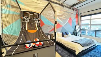 A room with a bed, a basketball hoop, and a large window.