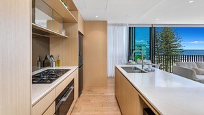 A modern kitchen with a built-in stove, oven, and a view of the ocean through large windows. - Ocean Views Palm Beach (Palm Beach)