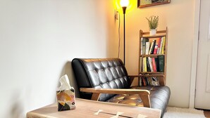 En hyggelig læsehjørne med en læderstol, et træbord, en bogreol og en lampe.