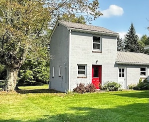 A two-story building with a red door, a small window, and a chimney. - Peaceful Escape • Hot Tub • Fire Pit • Views (Swan Lake)