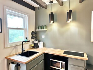 A kitchen with a sink, countertop, microwave, kettle, and hanging lights. - Peaceful Escape • Hot Tub • Fire Pit • Views (Swan Lake)