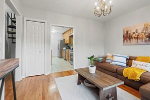 A modern living room with a brown leather sofa, a wooden coffee table, and a cityscape painting on the wall. - Spacious 4-bedroom apartment with WiFi, AC in enjoyable Newark (newark)
