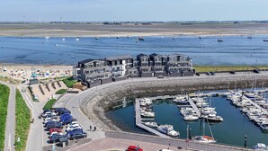 Un port de plaisance avec des bateaux, un espace de stationnement et des bâtiments dotés de balcons donnant sur l’eau.