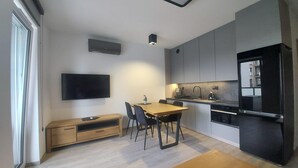 Una cocina moderna con comedor, televisor de pantalla plana montado en la pared y horno empotrado.