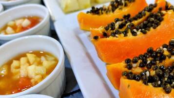 Un bufé con diversos platos, incluyendo papaya y una sopa con verduras picadas.