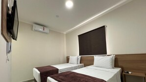 A hotel room with two single beds, a TV mounted on the wall, an air conditioning unit, and a wooden headboard. - HOTEL INTERNACIONAL GUARULHOS (Guarulhos)