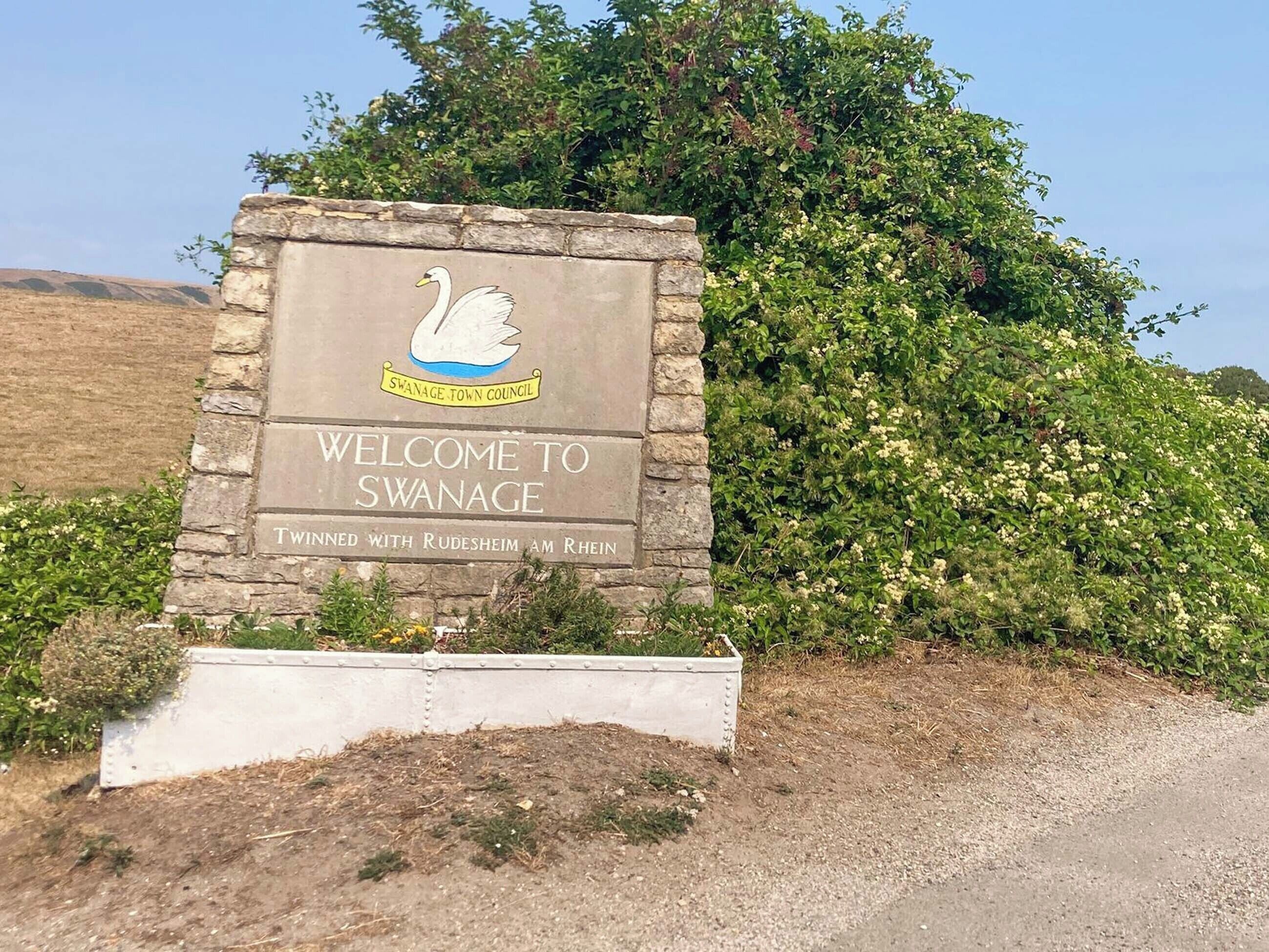 Swanageen johtava tervetulokyltti, jossa on joutsenlogo ja teksti, jossa toivotetaan vierailijat tervetulleiksi Swanageen, joka on ystävyskaupunki saksalaisen Rudesheim am Rheinin kanssa.