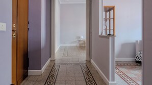 A hallway with a patterned floor, a wooden door, and a white wall with a shelf. - Sabina House a 10-minute walk from the Sistine Chapel and St. Peter's. (Roma)