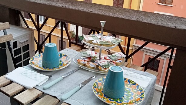 A balcony with a table set for two, featuring a blue mug, a plate with snacks, and a small tray of snacks. - Sabina House a 10-minute walk from the Sistine Chapel and St. Peter's. (Roma)