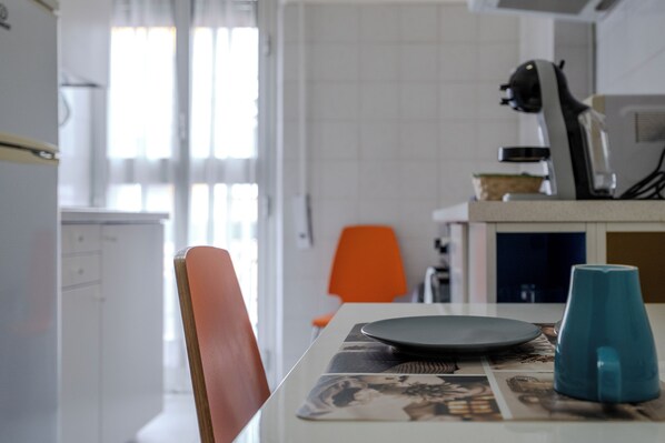 A dining table with a placemat, a blue mug, and a chair.