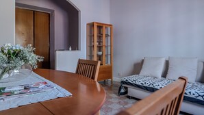 A dining area with a wooden table, a cabinet with glass doors, and a sofa with patterned cushions. - Sabina House a 10-minute walk from the Sistine Chapel and St. Peter's. (Roma)