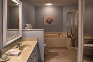 Une salle de bain avec un grand miroir, un lavabo beige, une baignoire et un espace douche.