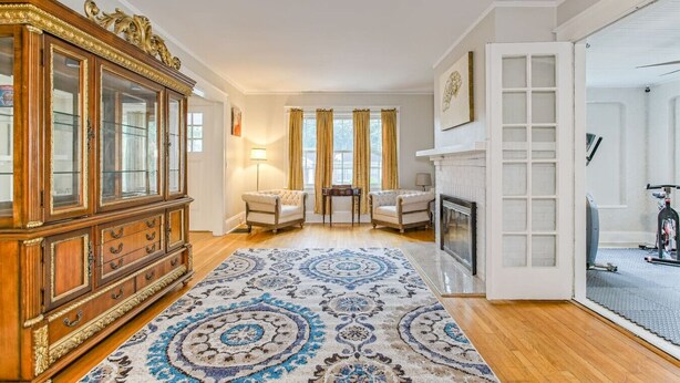 Un salon spacieux avec une grande armoire en bois, une cheminée et un tapis à motifs.
