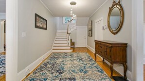Un couloir avec un escalier, une armoire en bois et un tapis à motifs.