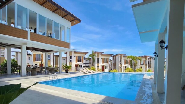 A modern resort with a swimming pool, covered outdoor seating, and a clear blue sky. - Minutes away with famous beaches and Cave. (Biking Dauis)