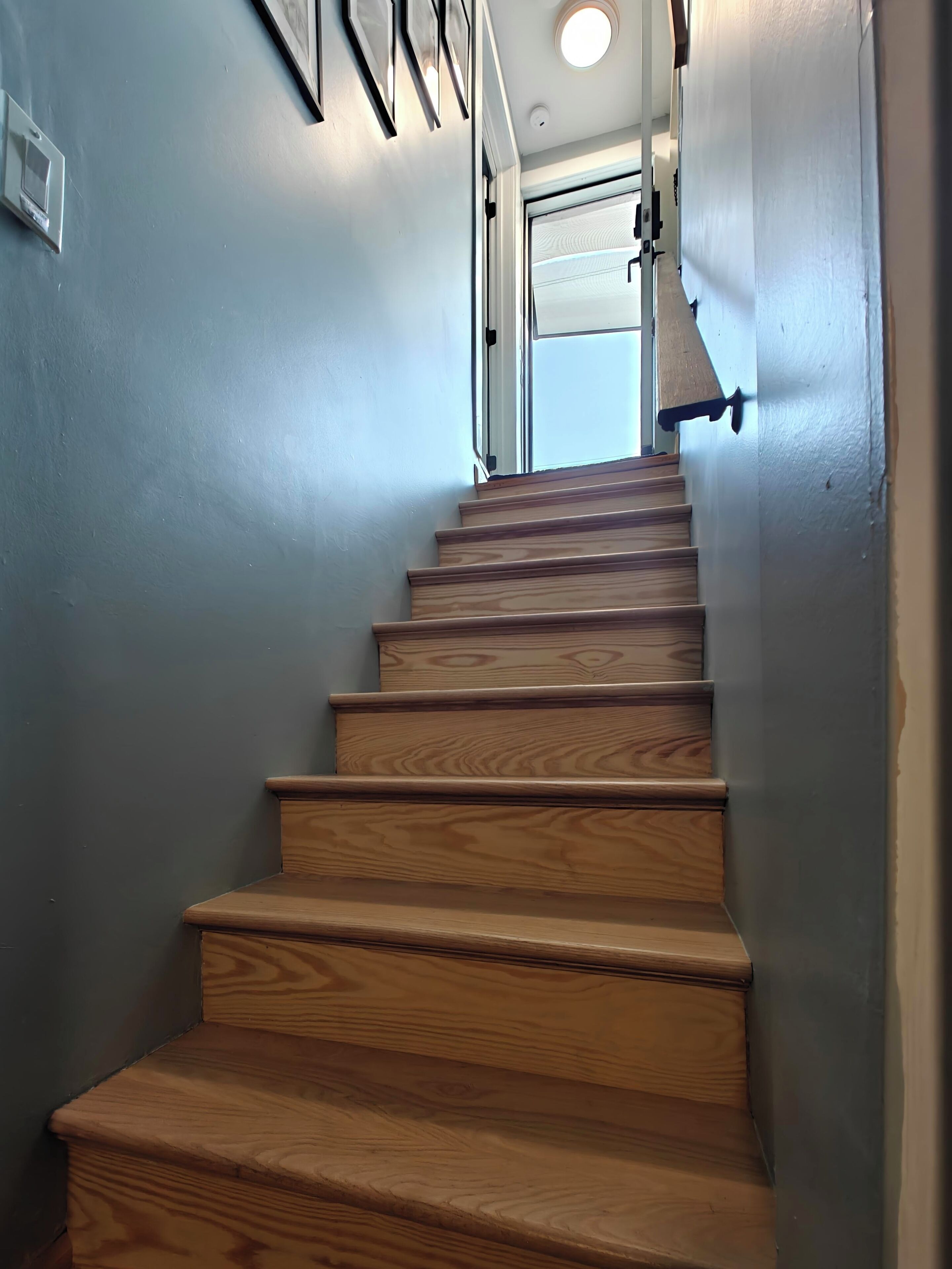 A wooden staircase with a handrail and a light fixture at the top.