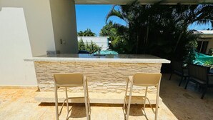 A kitchen area with a stone countertop and two chairs.