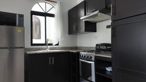 A kitchen with dark cabinets, a stainless steel refrigerator, a stove, and a microwave.