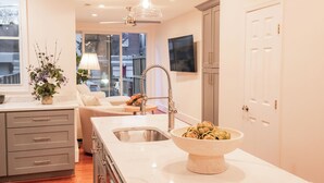 A modern kitchen with a large island, stainless steel appliances, and pendant lighting.