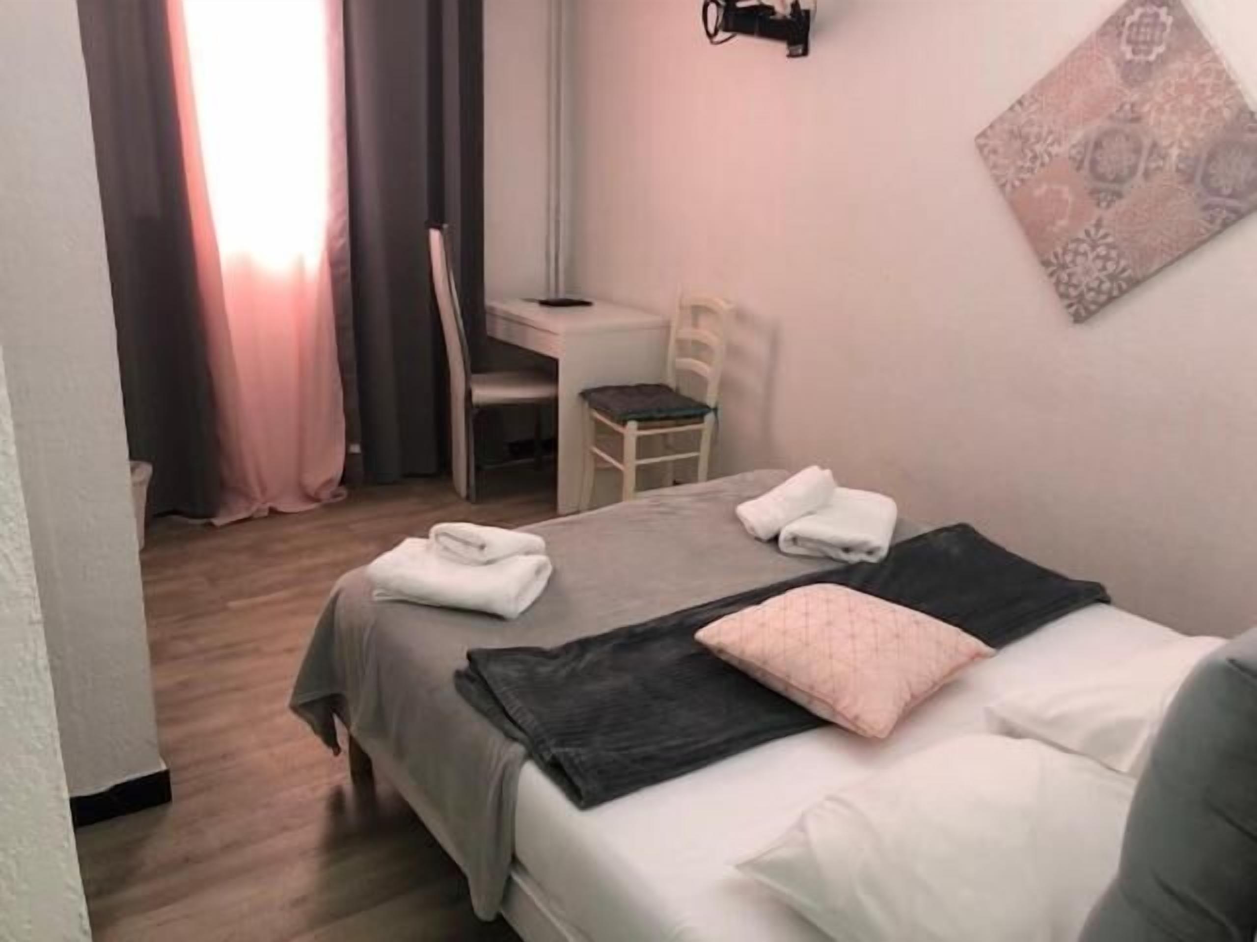 A neatly arranged bedroom with a bed, a desk, and a chair. There are towels on the bed.