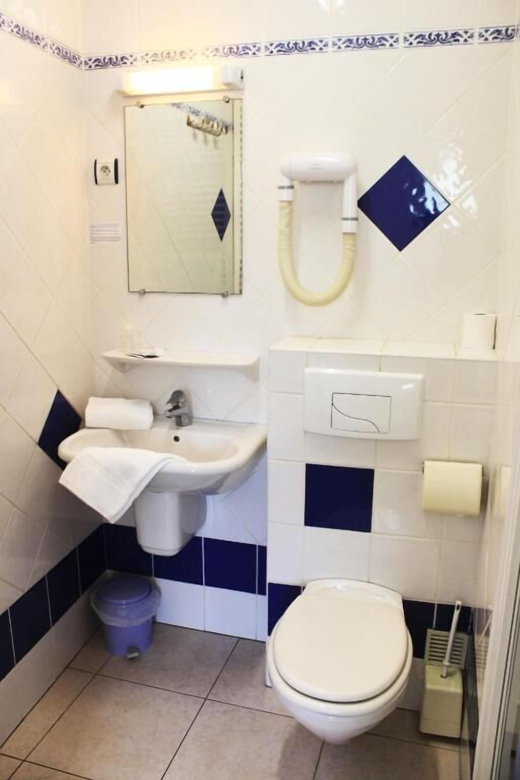 Un baño con lavamanos, inodoro y espejo.